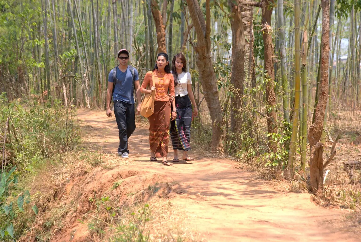 Jaden, Hnin Thuzar and Nu Nu walk together along a bamboo-lined path in Myanmar